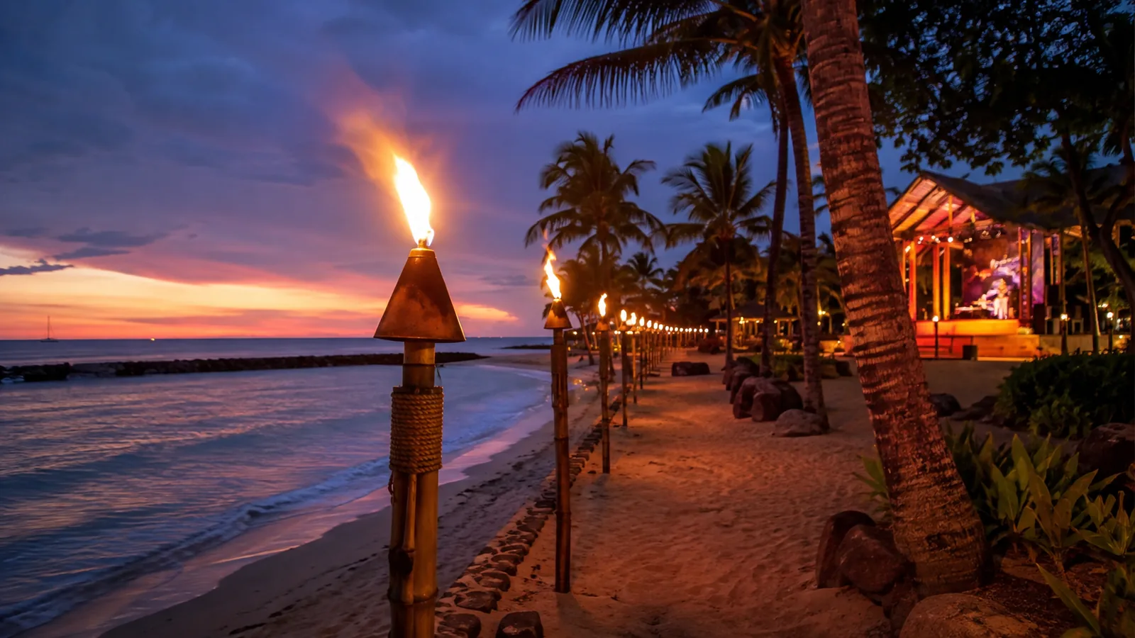 Tiki torches along a palm-lined Oahu beach at dusk